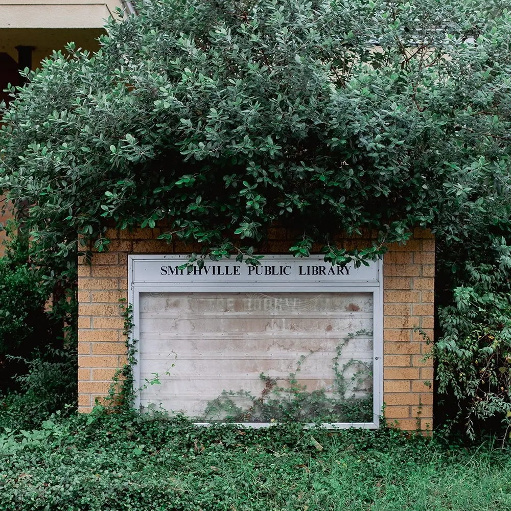 Smithville Public Library Sign surrounded by bushes.