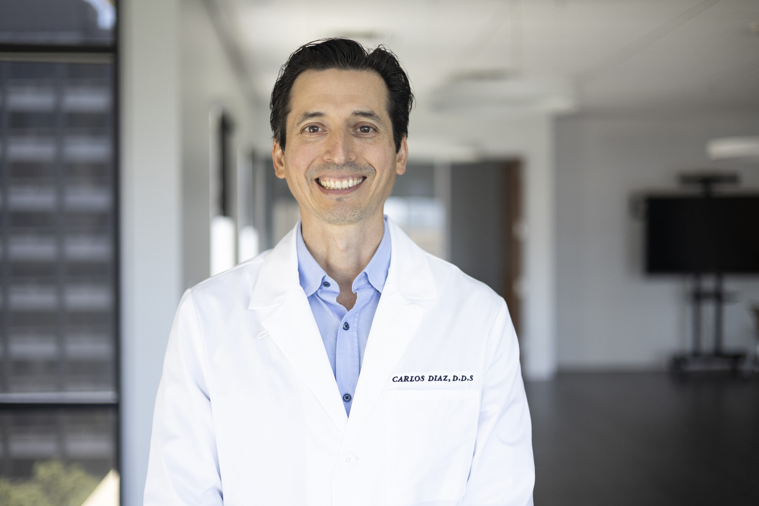 Dr. Carlos Diaz in a white coat standing for a portrait at St. David's Foundation